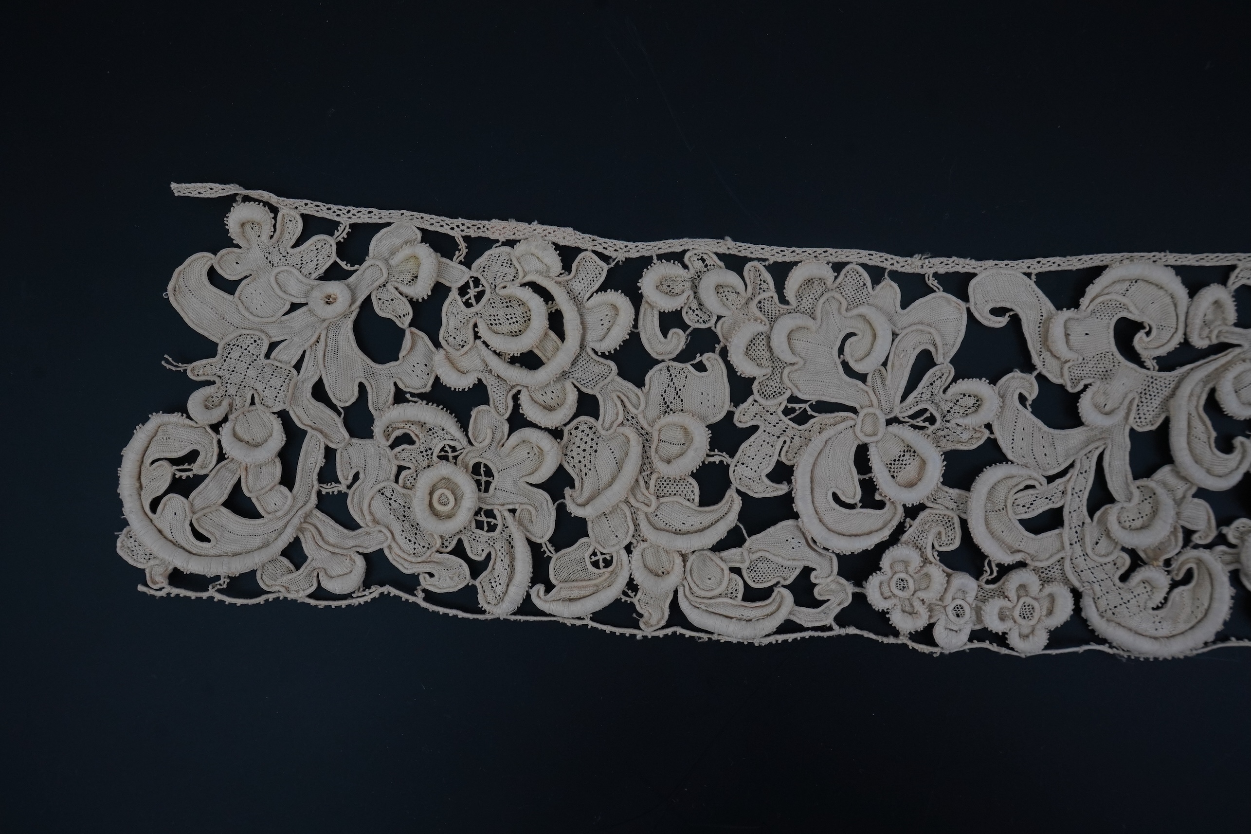 A length of 1660-1670 Italian Venetian Gros Point needle lace, this heavy needle lace was made with a wide cordonnet padded with wool, using close buttonhole stitch, to create large scrolling patterns in heavy relief, li